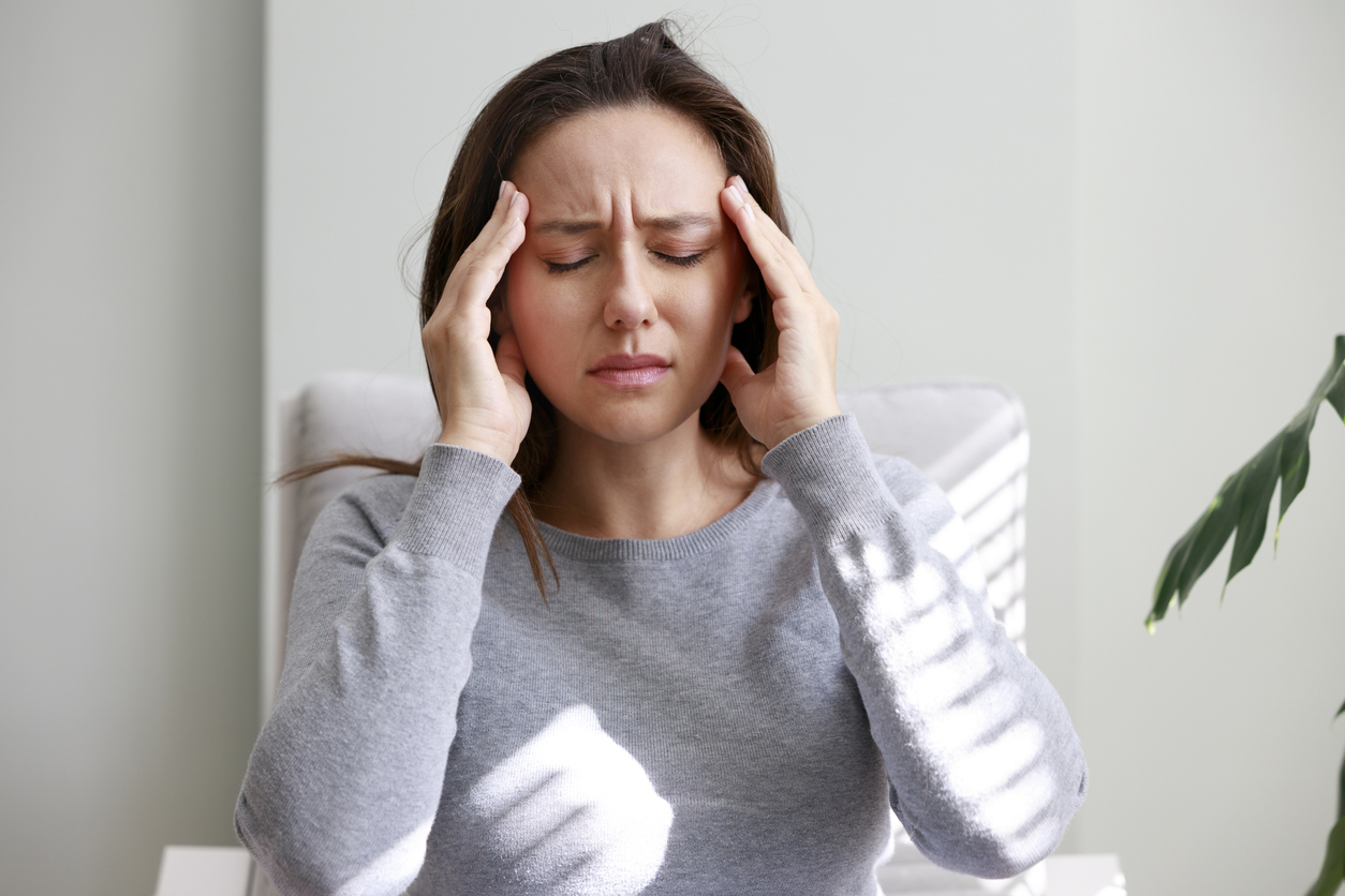 Woman rubbing her head in pain from TMJ disorder