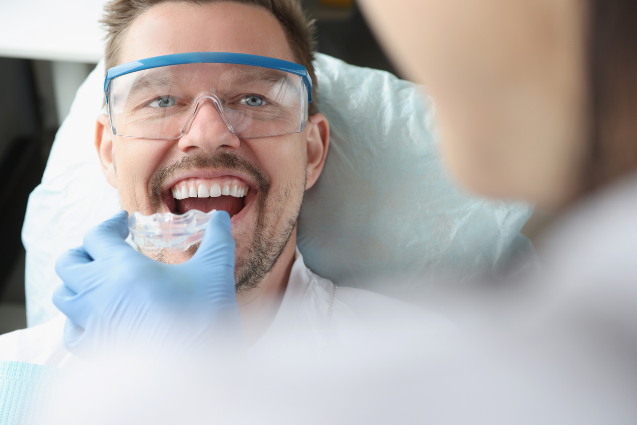 dentist places oral appliance in male patient's mouth