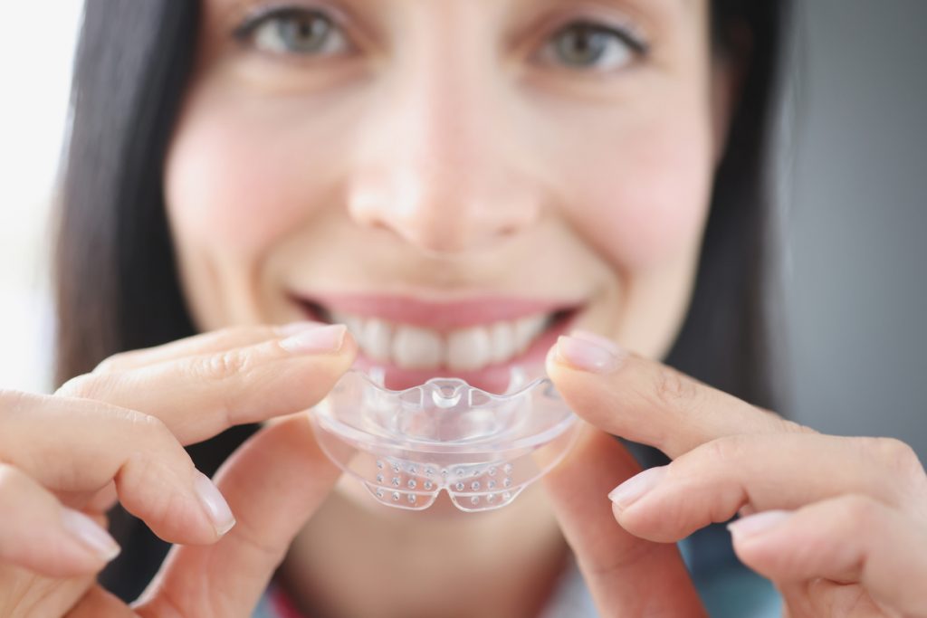 Woman holding a mouth guard to protect from sleep bruxism