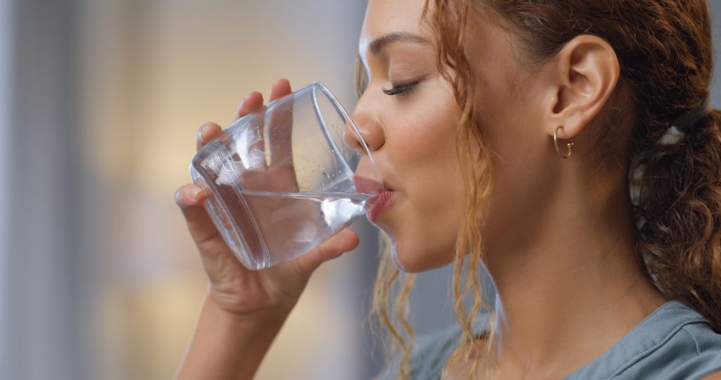 Woman drinking a glass of water refreshingly
