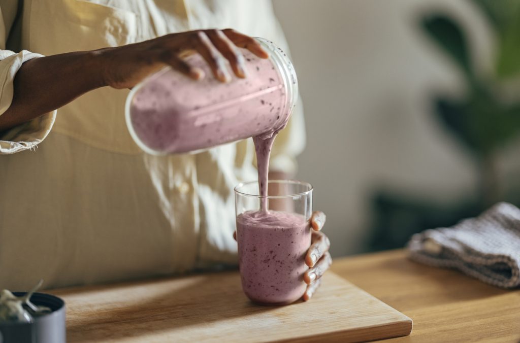 Woman pouring a thick fruit and yogurt smoothy