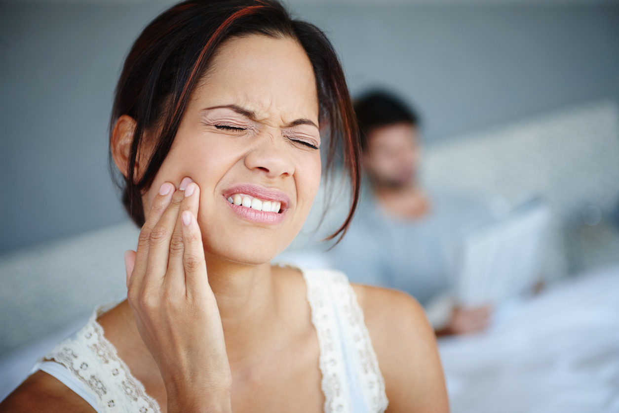 Woman with jaw pain holding her jaw