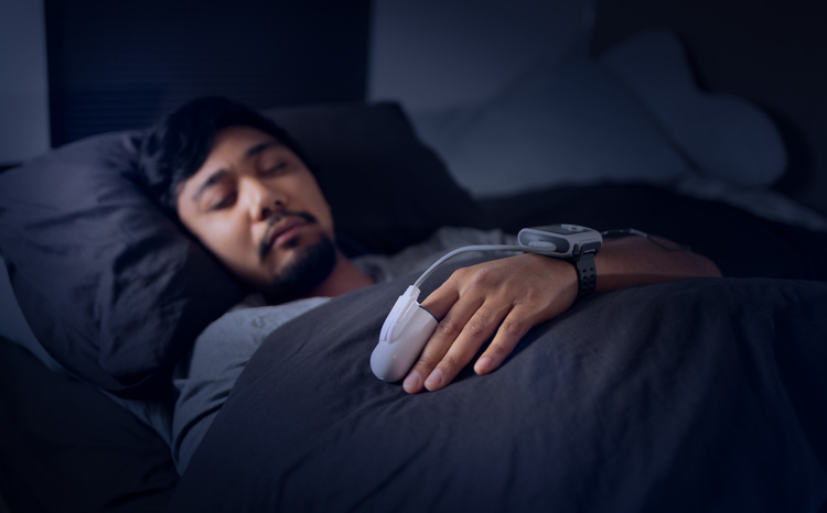 Man Wearing a Pulse Oximeter in Bed - At Home Sleep Study Test for Sleep Apnea.